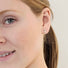young woman’s earlobe shows a Reiki imbued sterling silver crescent stud earring with a small white pearl nestled in the arc
