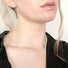 A closeup of a handcrafted necklace made with a strand of small oval freshwater white pearls