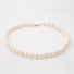consciously sourced, handcrafted freshwater pearl strand imbued with Reiki laying in a perfect circle on a white surface.