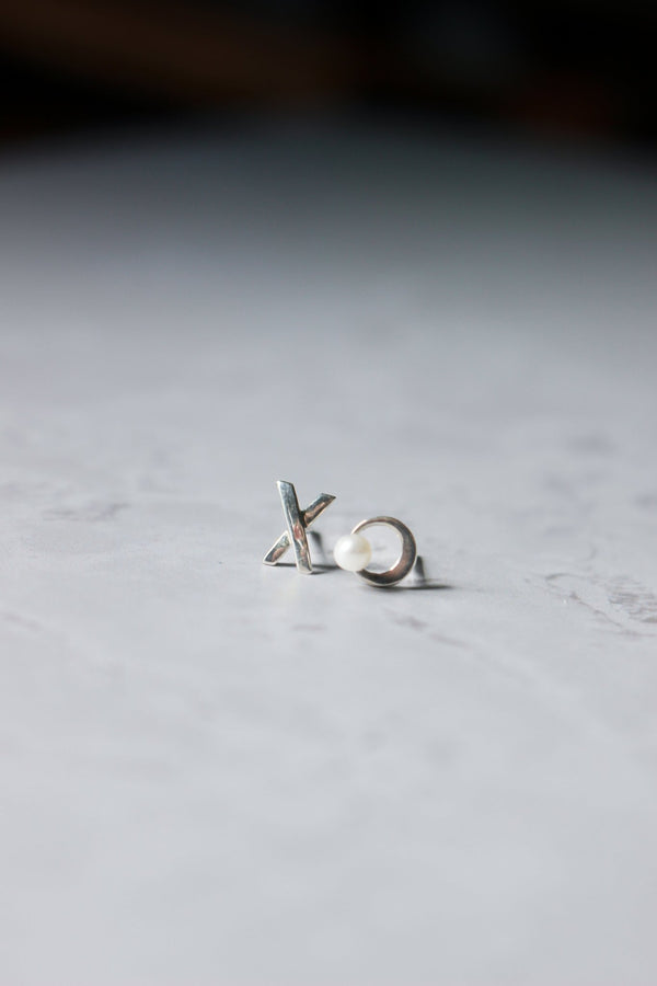 a pair of a-symmetrical studs. An X for one earlobe and a small for the other earlobe.open circle with a tiny pearl 